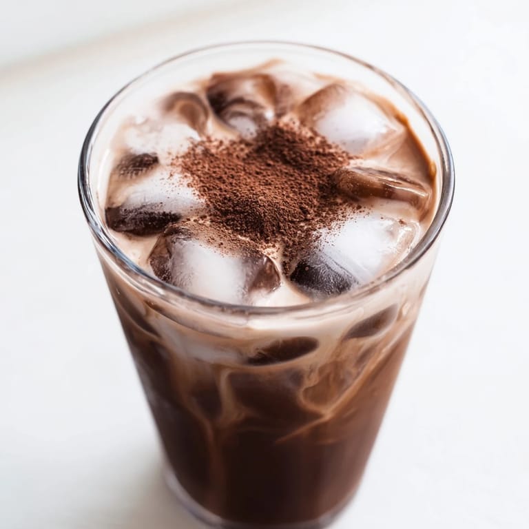 Close-up of a Milo ice latte, showcasing the rich chocolate color and creamy milk layers perfectly.