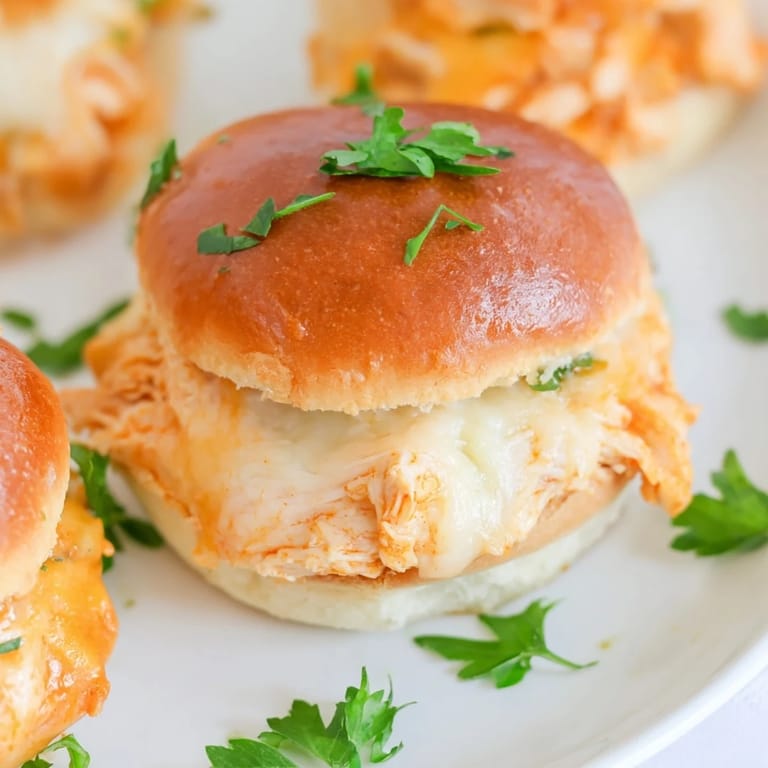 A serving of Pizza Dip Sliders on a rustic platter with celery sticks, highlighting bubbly cheese and buttery buns.