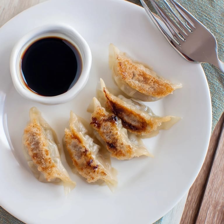 Homemade smashed gyozas arranged on a plate, revealing crispy edges and a savory pork filling for a quick appetizer.