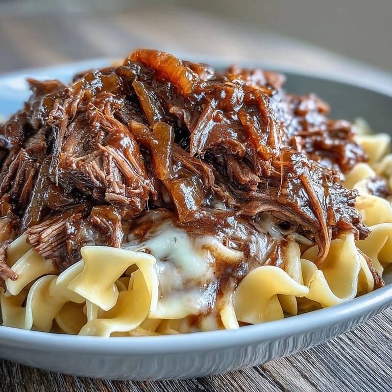 Steaming Crockpot French Onion Pot Roast Pasta plated with tender beef, caramelized onions, and melted Gruyère.